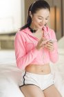 Chinese woman listening to music with smartphone in bedroom — Stock Photo
