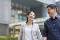 Счастливая взрослая китайская пара, идущая и держащаяся за руки — стоковое фото