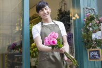 Chinese florist holding bunch of pink roses — Stock Photo