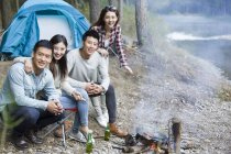 Amis chinois assis à côté du feu de camp et la préparation de la nourriture — Photo de stock