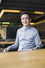 Chinese male IT worker sitting in chair at workplace — Stock Photo