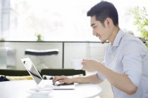 Homem chinês usando laptop no café — Fotografia de Stock