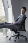 Китайський бізнесмен, сидячи в кріслі і дивлячись в камери — стокове фото