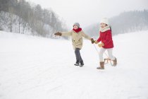 Китайские дети бегают с санями в снежном парке — стоковое фото