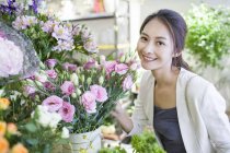 Mujer china posando con flores en la tienda - foto de stock