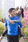 Mature chinese woman riding piggyback on man — Stock Photo