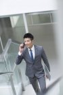 Hombre de negocios chino hablando por teléfono en la oficina - foto de stock