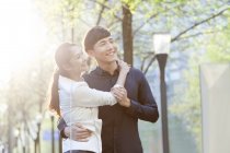 Chinese couple embracing on street and looking away — Stock Photo