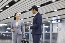 Китайские бизнесмены разговаривают в аэропорту с чемоданами — стоковое фото