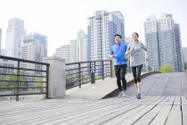 Chinese mature couple running on city bridge — Stock Photo