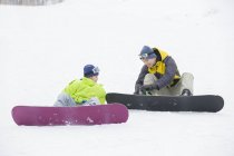 Père chinois aidant son fils à porter des vêtements de snowboard sur la neige — Photo de stock
