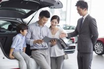 Chinese family with son choosing car with dealer — Stock Photo