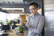Китаєць за допомогою смартфона в офісі — стокове фото