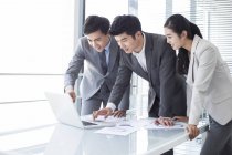 Uomini d'affari cinesi che usano laptop alla riunione — Foto stock