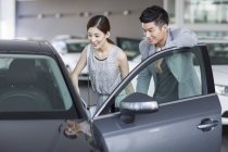 Casal chinês olhando para o carro no showroom — Fotografia de Stock