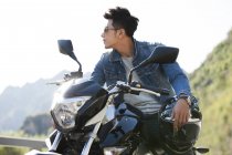Китаец сидит на мотоцикле на шоссе — стоковое фото