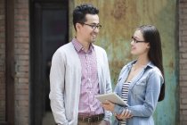 Chinese colleagues talking on street with digital tablet — Stock Photo