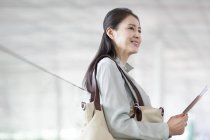 Зрілі Китайська жінка, що очікування в аеропорту з квитком — стокове фото