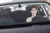 Chinese woman sitting in car and holding steering wheel — Stock Photo