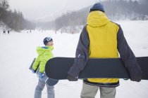 Padre e figlio che camminano con snowboard sulla neve, primo piano — Foto stock