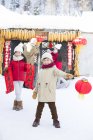 Niños chinos ayudando a los padres a decorar la puerta con linternas - foto de stock