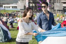 Chinese couple setting up tent on festival lawn — Stock Photo