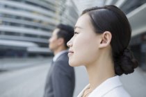 Chinese businesswoman and businessman looking at view, side view — Stock Photo