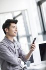 Китайский бизнесмен использует смартфон в офисе — стоковое фото