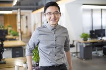 Chinese man standing in office and looking in camera — Stock Photo
