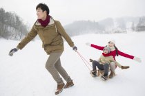 Uomo cinese tirando slitta con la famiglia sulla neve — Foto stock