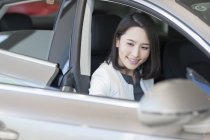 Joven mujer china sentada en coche - foto de stock