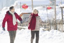 Chinese senior couple holding hands while walking outdoors — Stock Photo