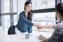 Chinese woman shaking hands on meeting — Stock Photo