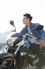 Uomo cinese seduto sulla moto in autostrada e guardando altrove — Foto stock