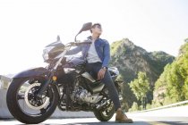 Uomo cinese seduto sulla moto in autostrada — Foto stock