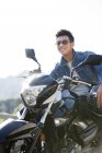 Uomo cinese seduto su moto in autostrada e sorridente — Foto stock