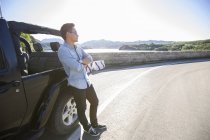 Chinese man leaning on car and looking away — Stock Photo