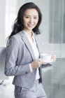 Chinese businesswoman taking coffee break at work — Stock Photo