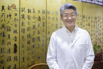 Старший китайський лікар, стоячи в клініку і дивлячись в камери — стокове фото