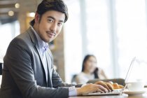 Homem de negócios chinês sentado com laptop no café — Fotografia de Stock