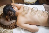 Woman lying down with vacuum cupping glass cups — Stock Photo