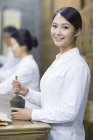 Chinese doctor using mortar and pestle in retro pharmacy — Stock Photo