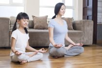Chinese mother and daughter meditating at home — Stock Photo
