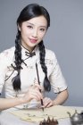 Chinese woman in traditional dress practicing calligraphy — Stock Photo