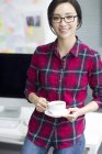 Chinese woman holding cup of coffee at office — Stock Photo