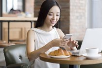 Mulher chinesa usando smartphone no café — Fotografia de Stock