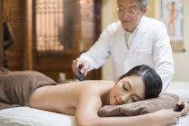 Senior Chinese doctor performing scrapping massage on female patient — Stock Photo