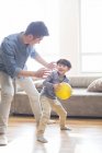 Chinês pai e filho brincando com bola amarela na sala de estar — Fotografia de Stock