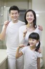 Китайские родители с дочерью чистят зубы — стоковое фото