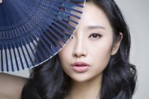 Китайська жінка, що охоплюють обличчя з розбірним вентилятор — стокове фото